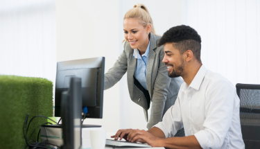 Two people at an office having a conversation in front of a computer