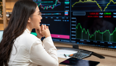 Woman in front of a monitor with line charts 