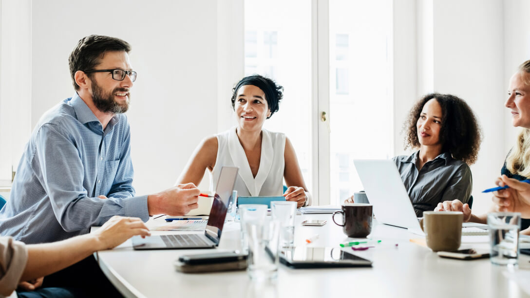 man leading a business meeting around a conference table
