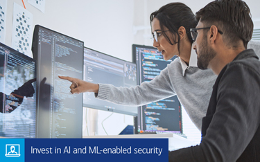 “Invest in AI and ML-enabled security” A man and woman reviewing code on a vertical computer monitor.