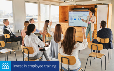 “Invest in employee training” A classroom with students and an instructor pointing at a whiteboard.