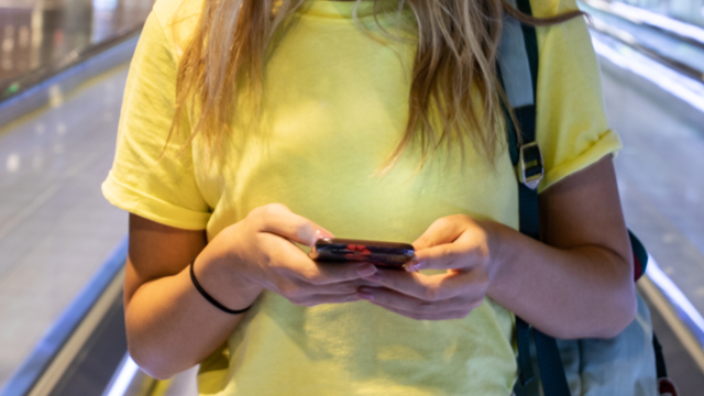 Woman in yellow shirt holding mobile phone.