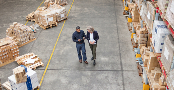 Warehouse supervisor walking and talking with senior manager