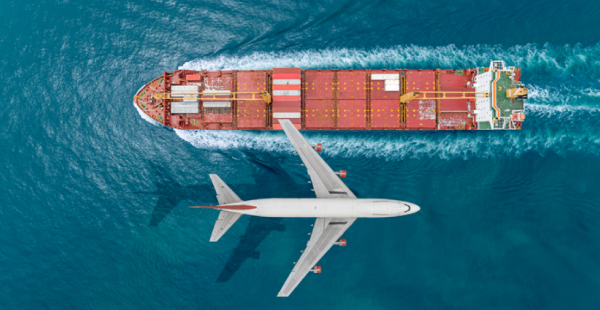 Passenger plane flying over the sea with cargo ship sailing on the sea