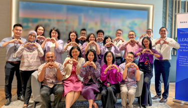 Sharing impact of inclusion in the workplace: A group of employees making heart symbols with their hands