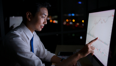 A man pointing at a chart on a monitor
