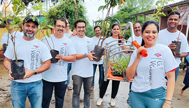 A group of employees carrying plants for plantation.