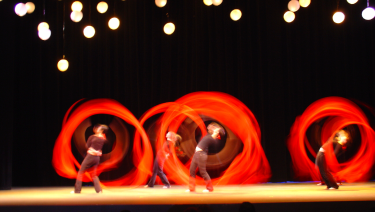 Dancers on stage with red ribbons