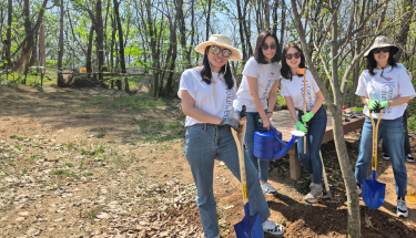 Environmental sustainability: Volunteers with shovels and a watering can outside 