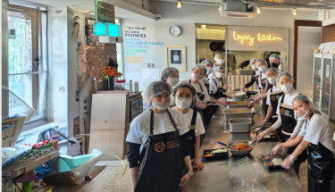 Hunger relief: Volunteers in aprons, hairnets and masks posing in a kitchen 