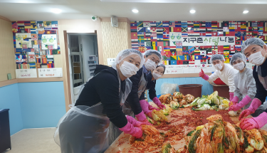 Providing migrants with hunger relief: Volunteers in masks, gloves and hairnets making kimchee 