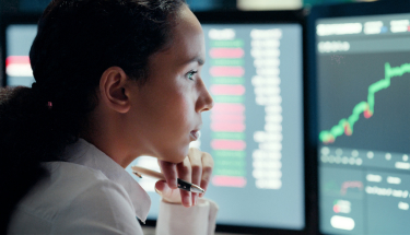 A woman in front of chart screens 