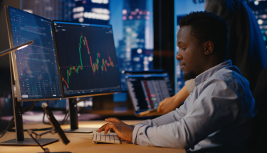 A man working in front of charts on a monitor
