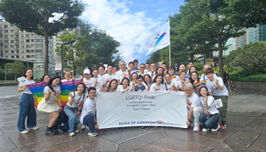 A group of people posing on the streets behind a banner 