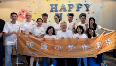 A group of people smiling and holding a banner