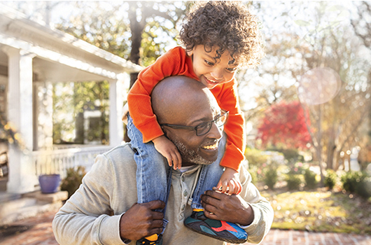 An older man carrying a young boy on his shoulders