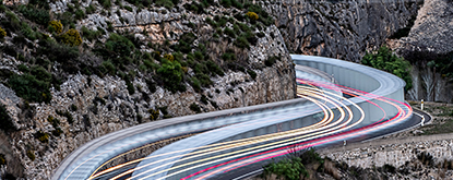 A winding cliff-side road with vehicles in motion 