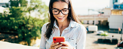 Woman in glasses smiling while using phone