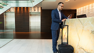 A businessman leaning against counter with mobile phone in his hand