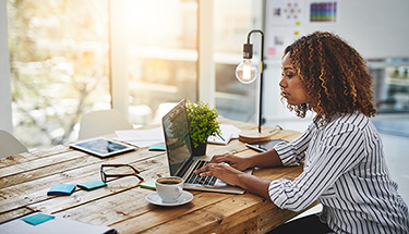 A businesswoman sitting at a desk working on a laptop