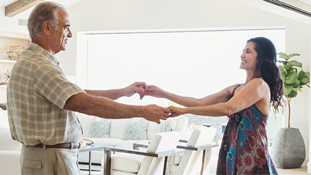 A retirement-age couple dancing in their home