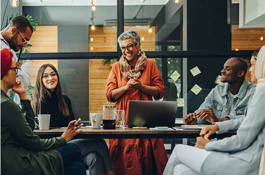 A diverse group of coworkers talking and laughing at work in a meeting