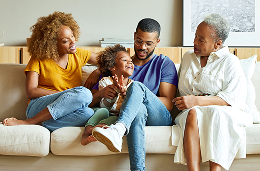 Mom, child, dad and grandmother sitting on the couch together and launching