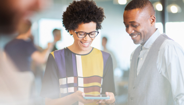 Two people smiling and looking at a phone 